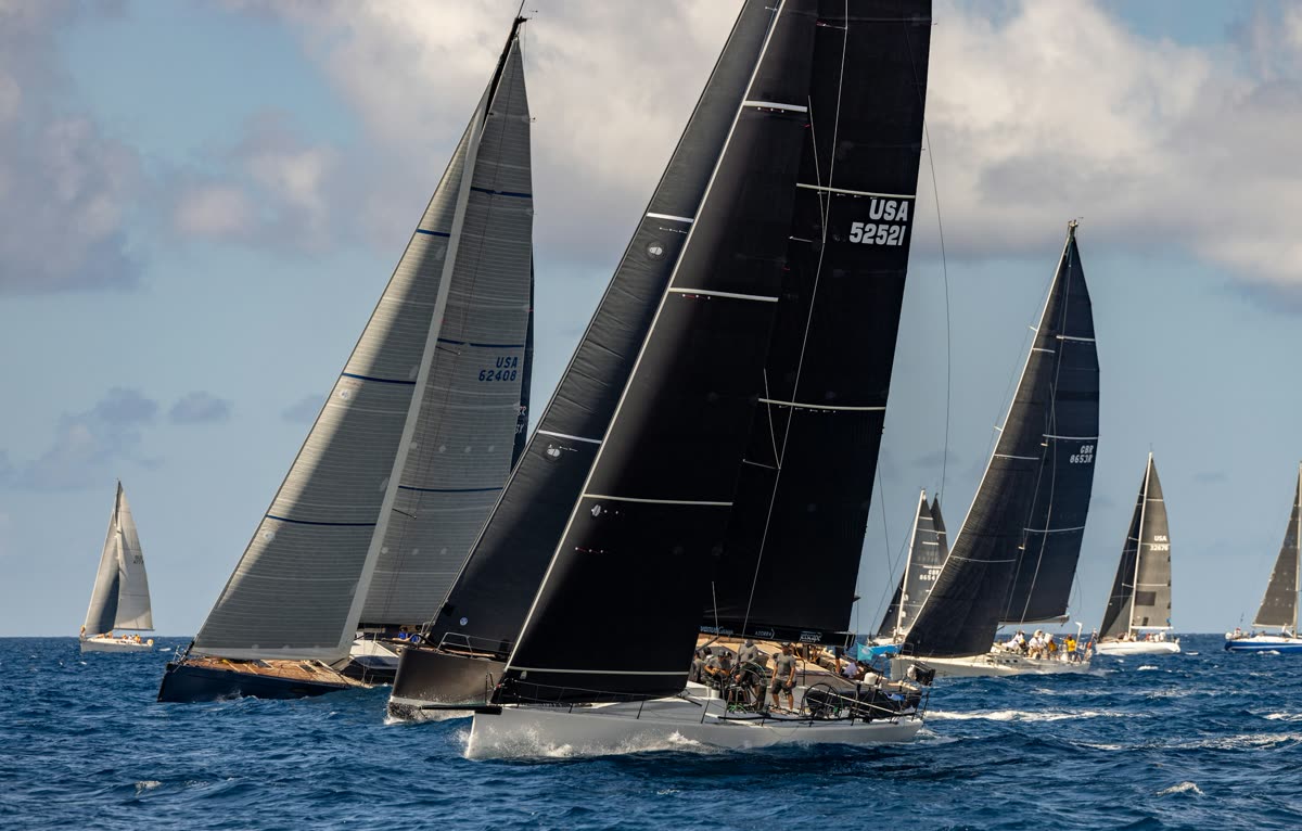 Flotte de voiliers de course aux voiles noires en régate sur une mer bleu profond