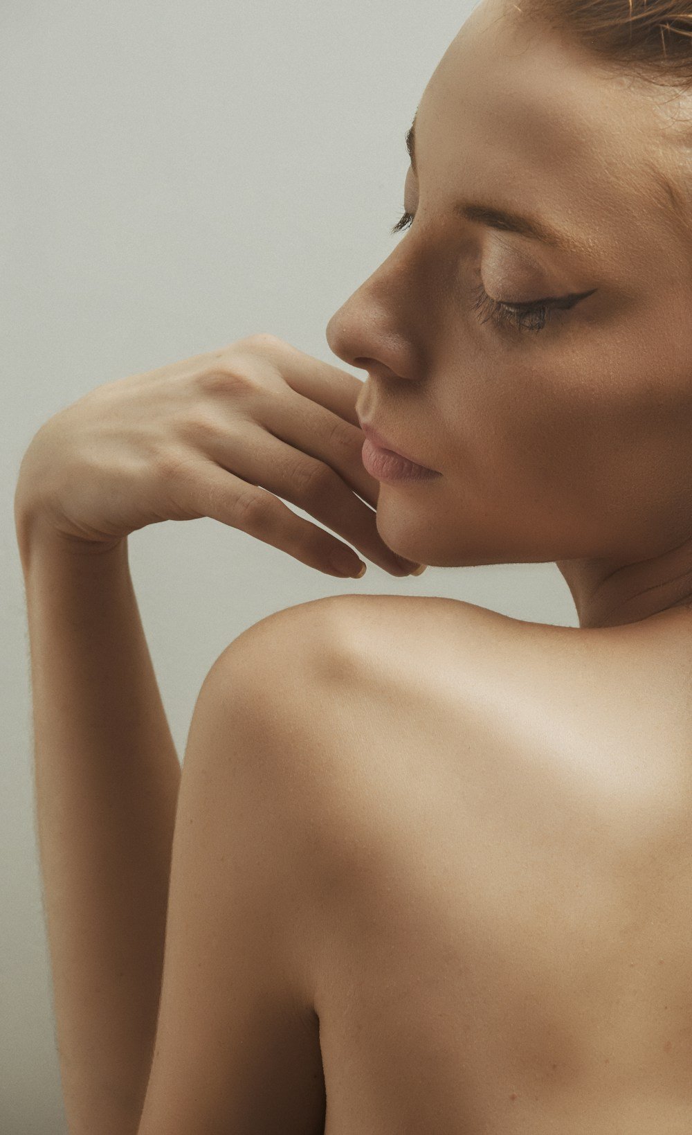 Profile of woman with bare shoulder, hand touching her face