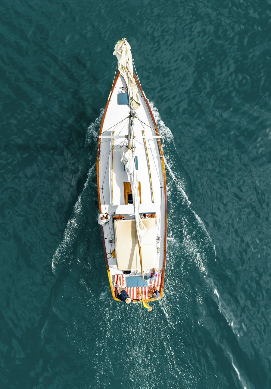 Aerial view of classic yacht, wake cutting through turquoise waters